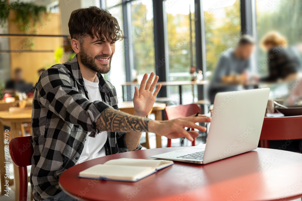 Young man in plaid shirt sitting at laptop and having a video call Young man in plaid shirt sitting at laptop and having a video call