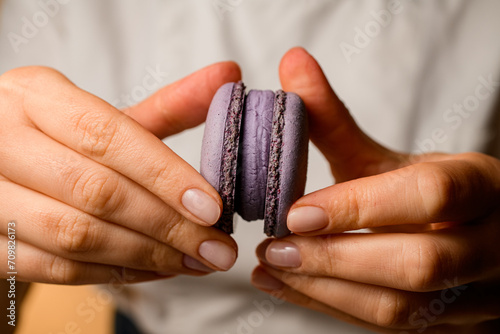 Close-up female hands of a confectioner fasten the halves of purple macaroons