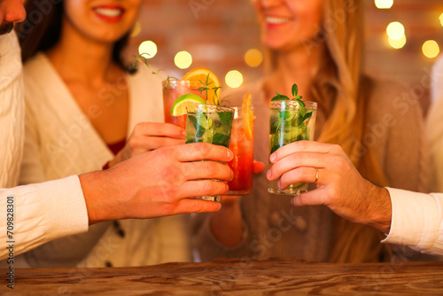Canvas Print Young men and women drinking cocktail at party