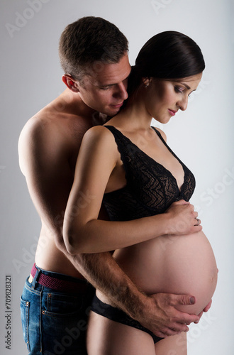 Young man and pretty pregnant woman embrace