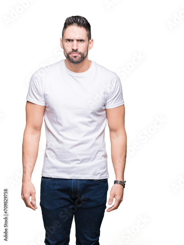 Young man wearing casual white t-shirt over isolated background skeptic and nervous, frowning upset because of problem. Negative person.