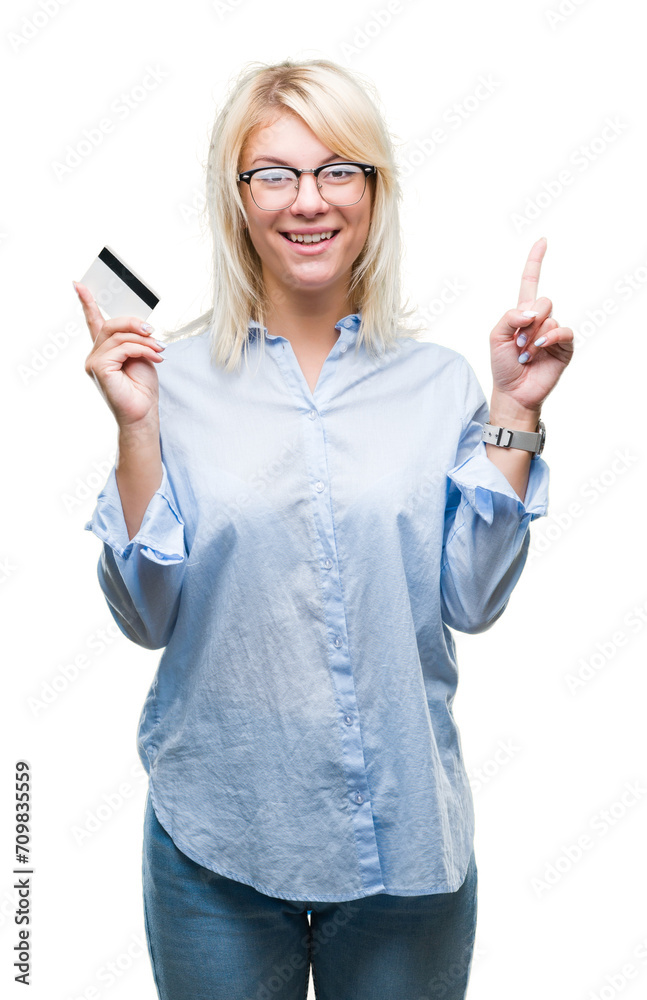 Obraz premium Young beautiful blonde business woman holding credit card over isolated background surprised with an idea or question pointing finger with happy face, number one