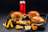 Tasty big burger and fries with can of cola on wooden background. Takeaway fast food