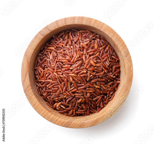 Red rice in a wooden plate close-up on a white. Top view