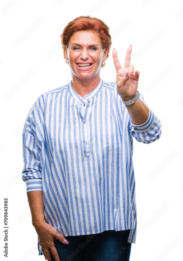Naklejka premium Atrractive senior caucasian redhead woman over isolated background smiling with happy face winking at the camera doing victory sign. Number two.