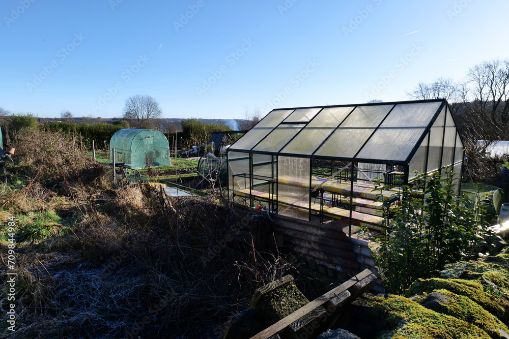 Allotment for growing vegetables, shot on a bright and sunny winters day. A glass greenhouse, polytunnel, and other growing areas can be seen. Allotment for growing vegetables, shot on a bright and sunny winters day. A glass greenhouse, polytunnel, and other growing areas can be seen.