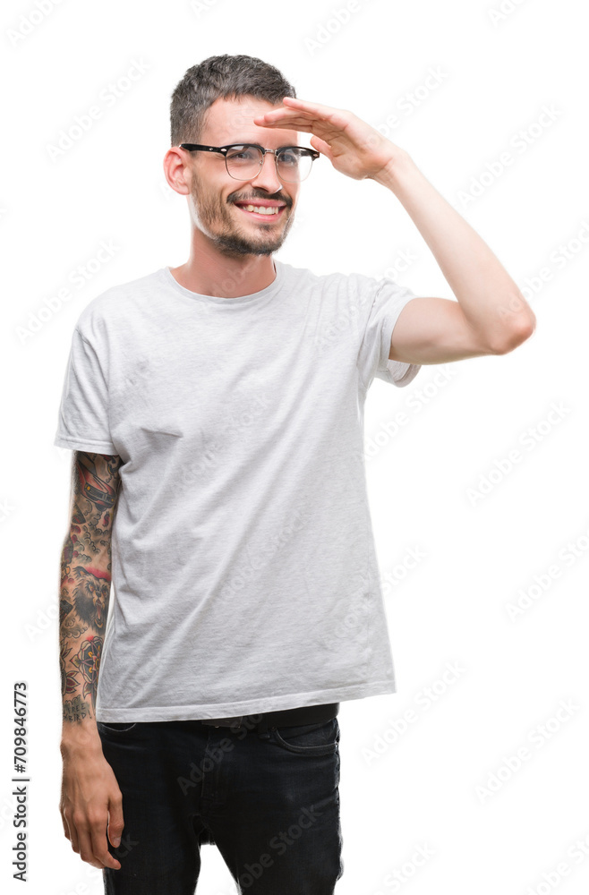 Young tattooed adult man very happy and smiling looking far away with hand over head. Searching concept. Young tattooed adult man very happy and smiling looking far away with hand over head. Searching concept.