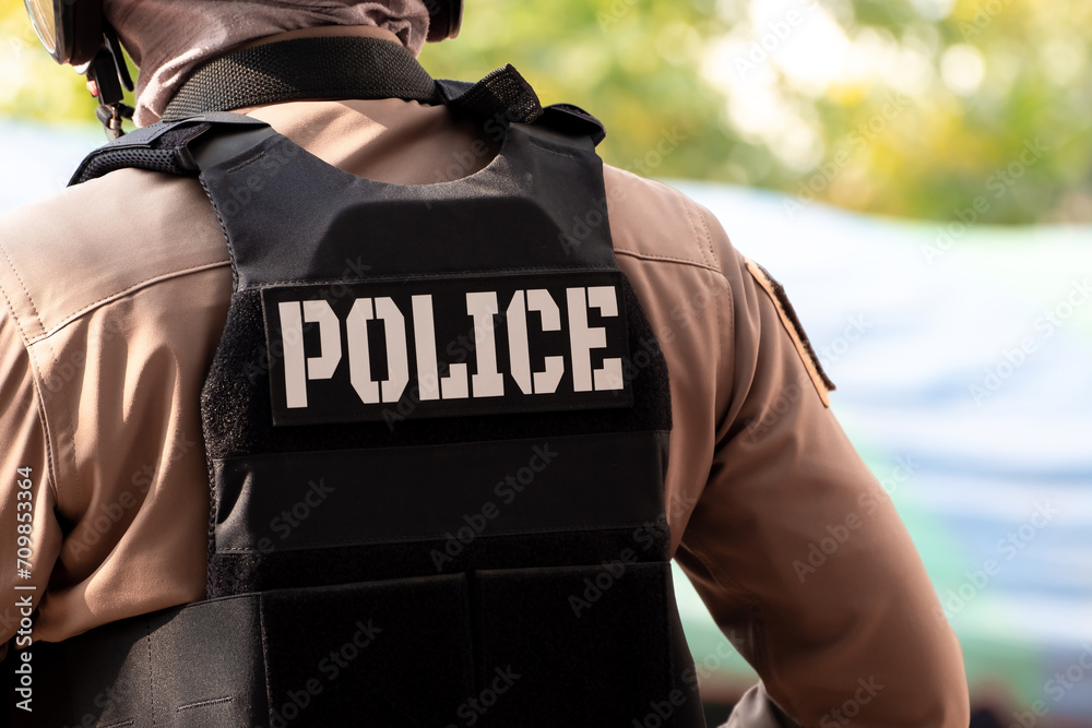 Back view of male police officer dressed. A bullet proof vest on his back spells out the word police. Thailand police uniform, Protection and maintenance of peace and order Back view of male police officer dressed. A bullet proof vest on his back spells out the word police. Thailand police uniform, Protection and maintenance of peace and order