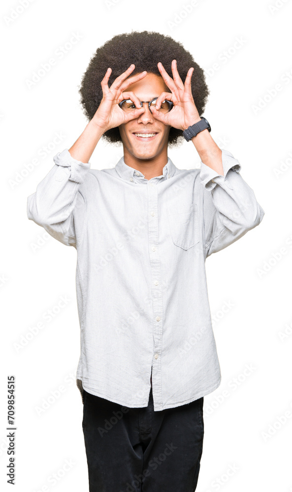 Young african american man with afro hair wearing glasses doing ok gesture like binoculars sticking tongue out, eyes looking through fingers. Crazy expression. Young african american man with afro hair wearing glasses doing ok gesture like binoculars sticking tongue out, eyes looking through fingers. Crazy expression.