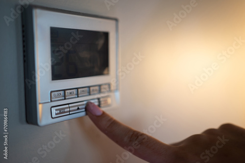 Close-up of a girl using the air conditioning remote control at night.