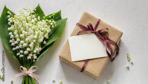 Blank greeting card with Lily of the valley flowers bouquet and gift box on white background. Wedding invitation. Womens day, Valentines day card. Mock up. Flat