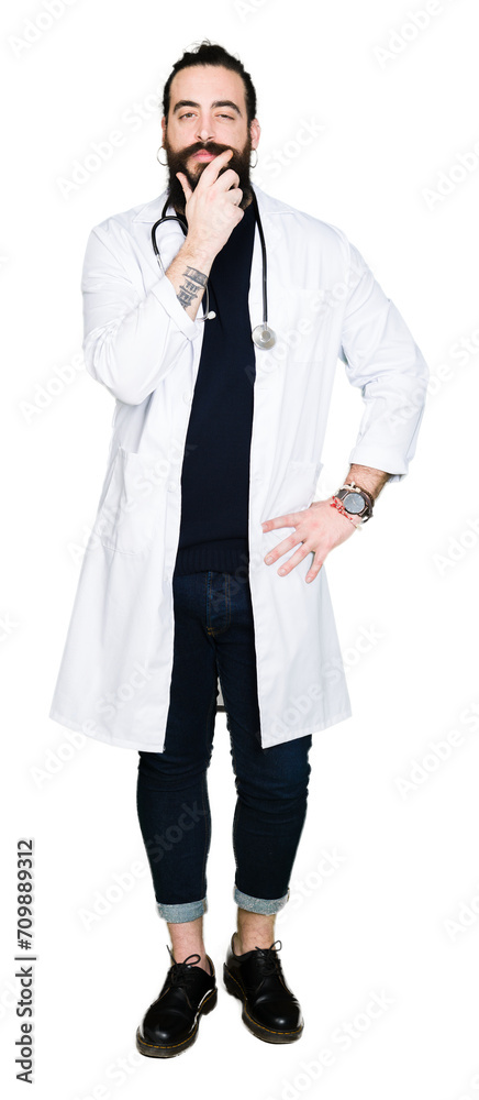 Doctor with long hair wearing medical coat and stethoscope looking confident at the camera with smile with crossed arms and hand raised on chin. Thinking positive. Doctor with long hair wearing medical coat and stethoscope looking confident at the camera with smile with crossed arms and hand raised on chin. Thinking positive.