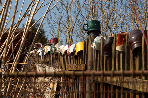 multicolored mugs arranged on a weathered and rustic wooden fence
