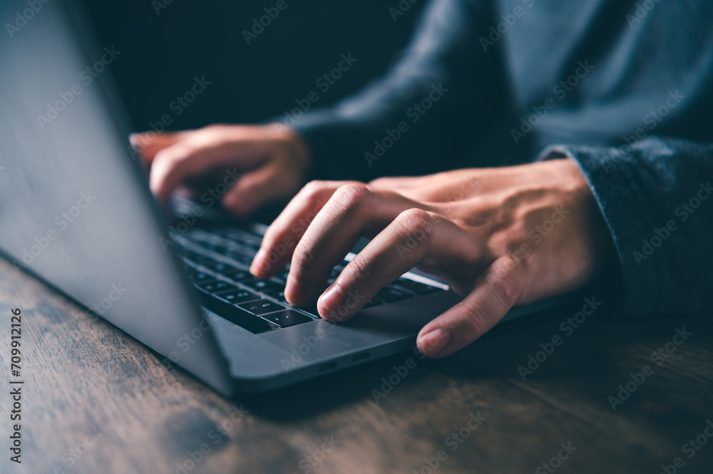 Close-up of hands typing on a laptop keyboard in the night at home office with a blurred background. Close-up of hands typing on a laptop keyboard in the night at home office with a blurred background.