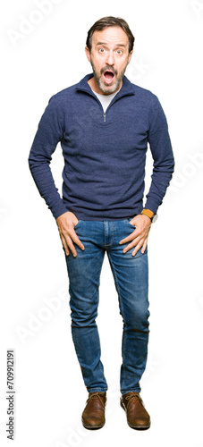 Middle age handsome man wearing a sweater afraid and shocked with surprise expression, fear and excited face.