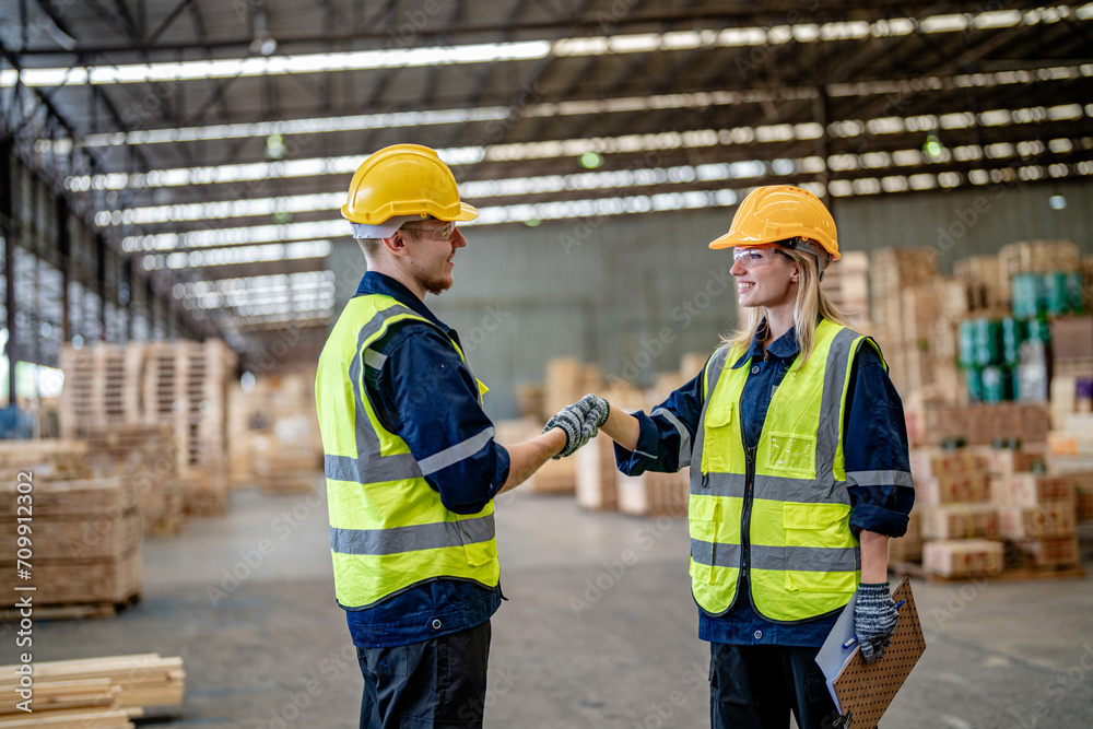 workers man and woman engineering walking and handshakeing with working suite dress at warehouse. Concept of smart industry worker operating. Wood factories produce wood palate workers man and woman engineering walking and handshakeing with working suite dress at warehouse. Concept of smart industry worker operating. Wood factories produce wood palate