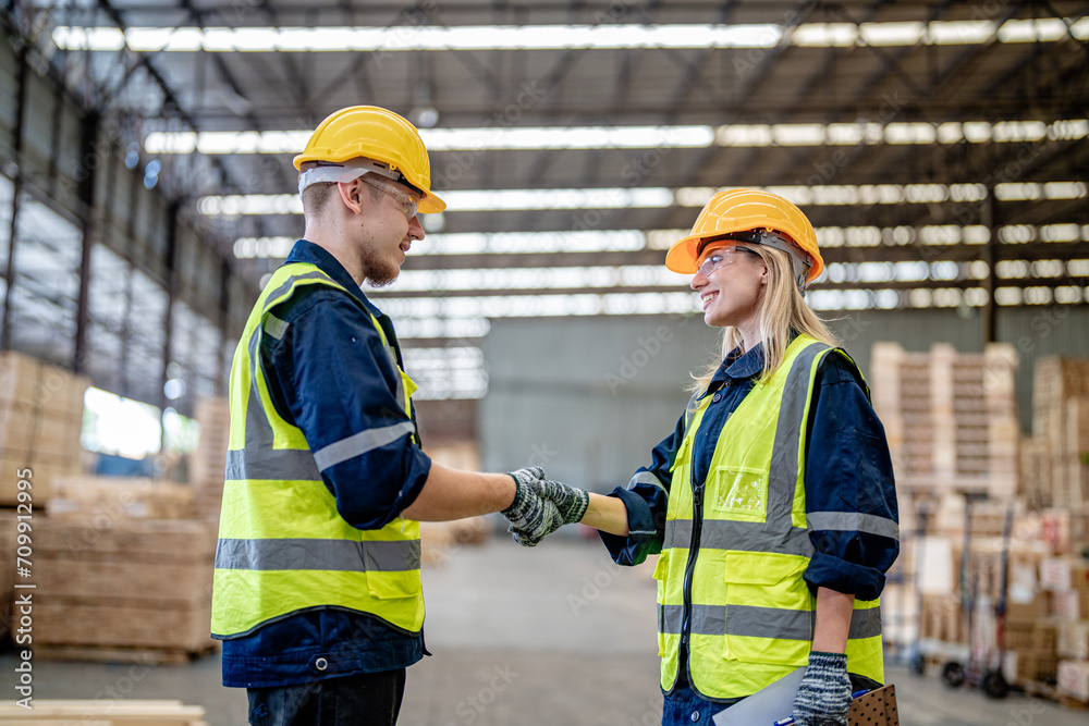 workers man and woman engineering walking and handshakeing with working suite dress at warehouse. Concept of smart industry worker operating. Wood factories produce wood palate workers man and woman engineering walking and handshakeing with working suite dress at warehouse. Concept of smart industry worker operating. Wood factories produce wood palate