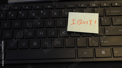 yellow adhesive note with handwritten captial-letter words "I quit" in red ink, placed on keyboard