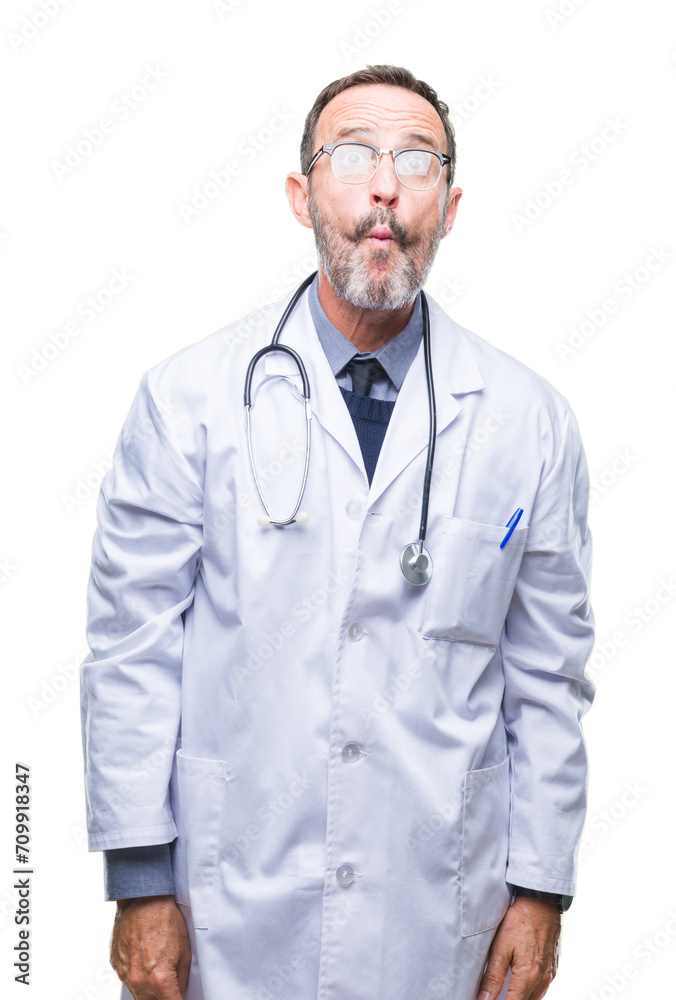 Middle age senior hoary doctor man wearing medical uniform isolated background making fish face with lips, crazy and comical gesture. Funny expression. Middle age senior hoary doctor man wearing medical uniform isolated background making fish face with lips, crazy and comical gesture. Funny expression.