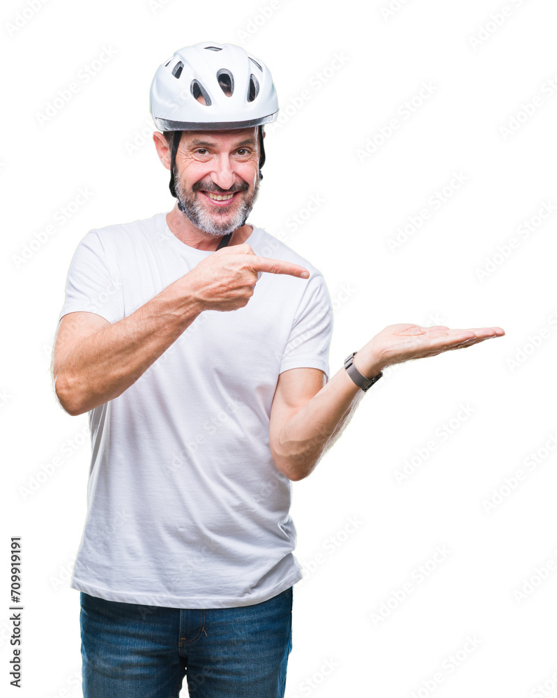 Middle age senior hoary cyclist man wearing bike safety helment isolated background amazed and smiling to the camera while presenting with hand and pointing with finger. Middle age senior hoary cyclist man wearing bike safety helment isolated background amazed and smiling to the camera while presenting with hand and pointing with finger.