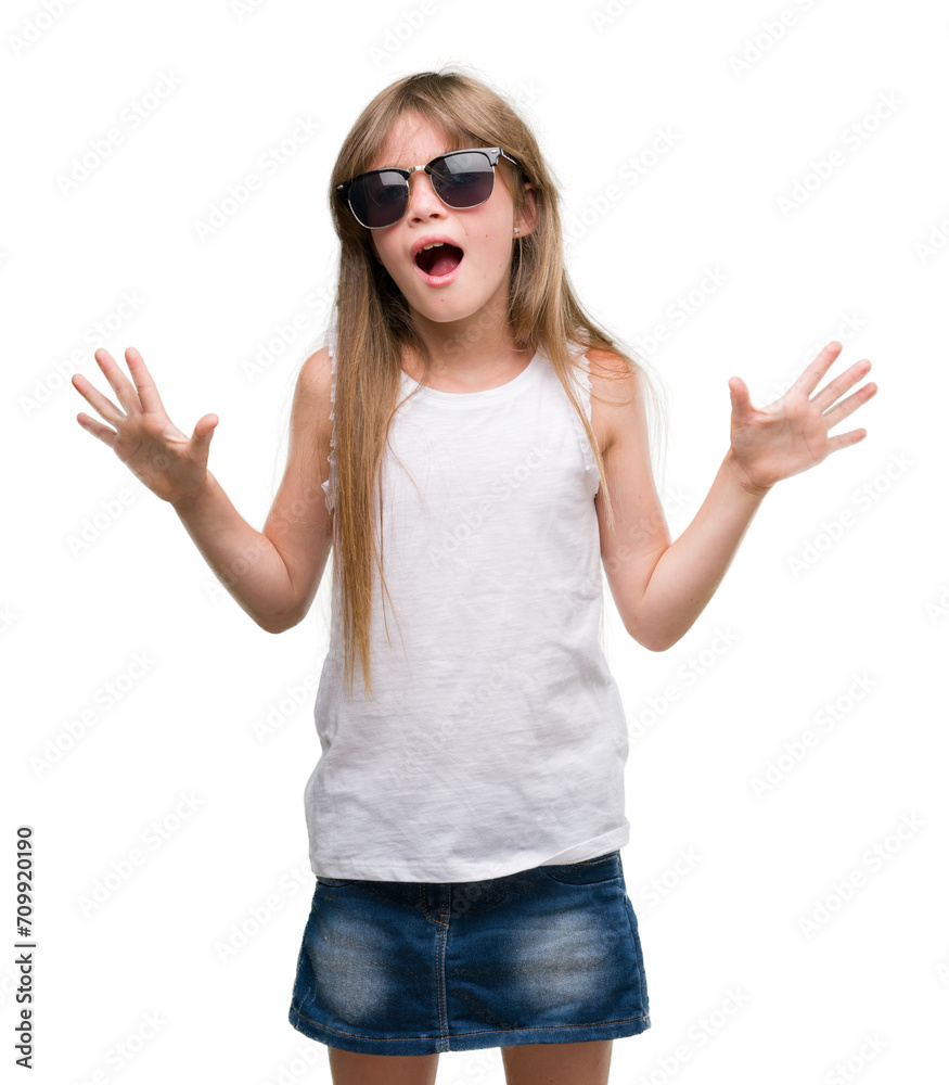 Young blonde toddler wearing sunglasses very happy and excited, winner expression celebrating victory screaming with big smile and raised hands Young blonde toddler wearing sunglasses very happy and excited, winner expression celebrating victory screaming with big smile and raised hands
