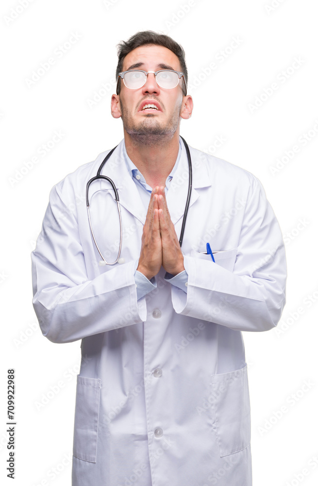 Handsome young doctor man begging and praying with hands together with hope expression on face very emotional and worried. Asking for forgiveness. Religion concept. Handsome young doctor man begging and praying with hands together with hope expression on face very emotional and worried. Asking for forgiveness. Religion concept.