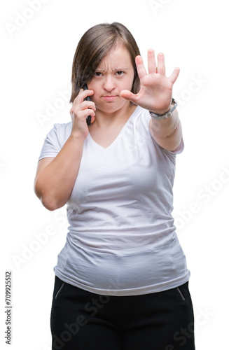 Young adult woman with down syndrome taking using smartphone over isolated background with open hand doing stop sign with serious and confident expression, defense gesture