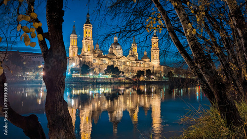 Evening Radiance: Zaragoza's skyline adorned with the Basilica del Pilar, a crescent moon, and the Stone Bridge, creating a mesmerizing tapestry of illuminated beauty.
 photo