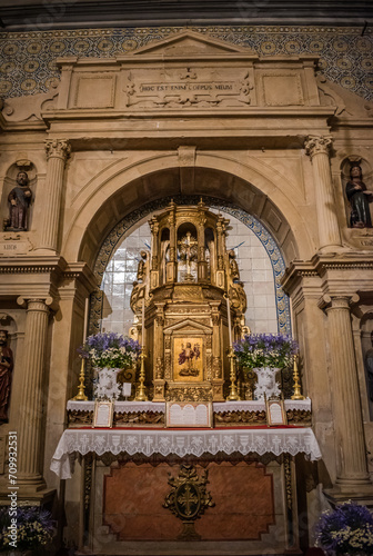 Detail of stonework altar with evangelist niches and arch with golden tabernacle in the center of tiles in low light, Dornes PORTUGAL photo