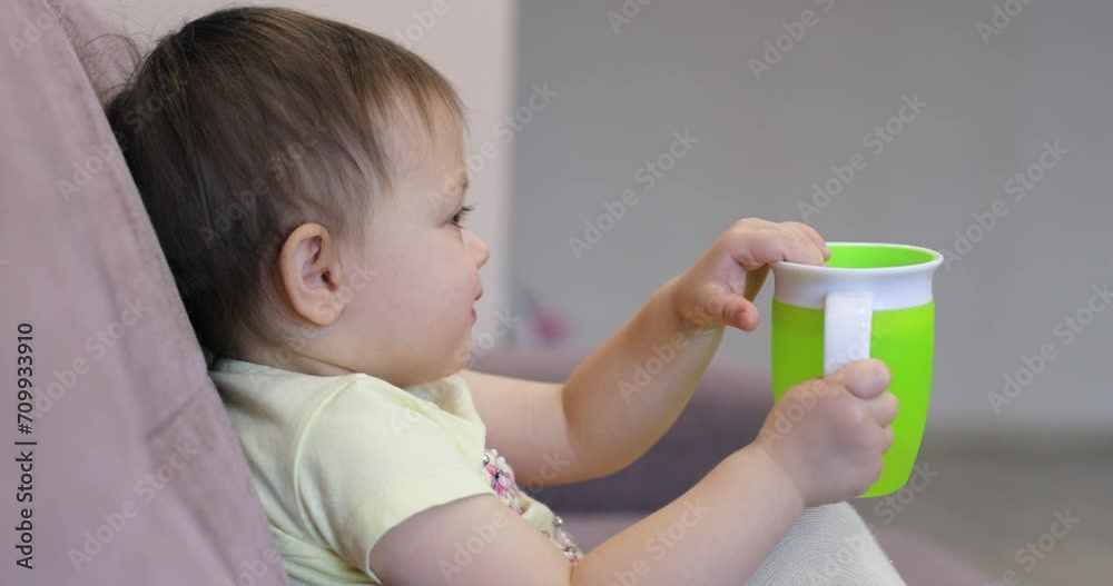 little baby child with water bottle watching tv sitting on coach at home little baby child with water bottle watching tv sitting on coach at home