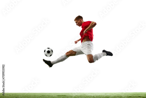 Aerial Symphony of Soccer. Athleticism. Portrait of soccer maestro orchestrates airborne pass, the ball dancing through air against white background with green field. Concept of sport games, match. © Lustre