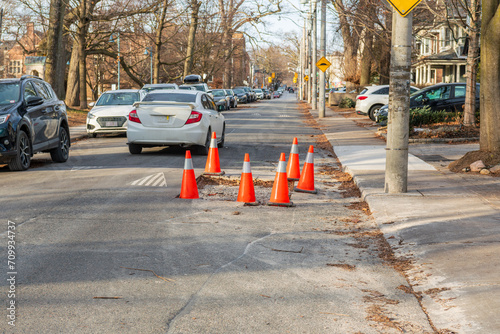 Photography road repair:  car manouvers around a hole coned off on a residential street in w