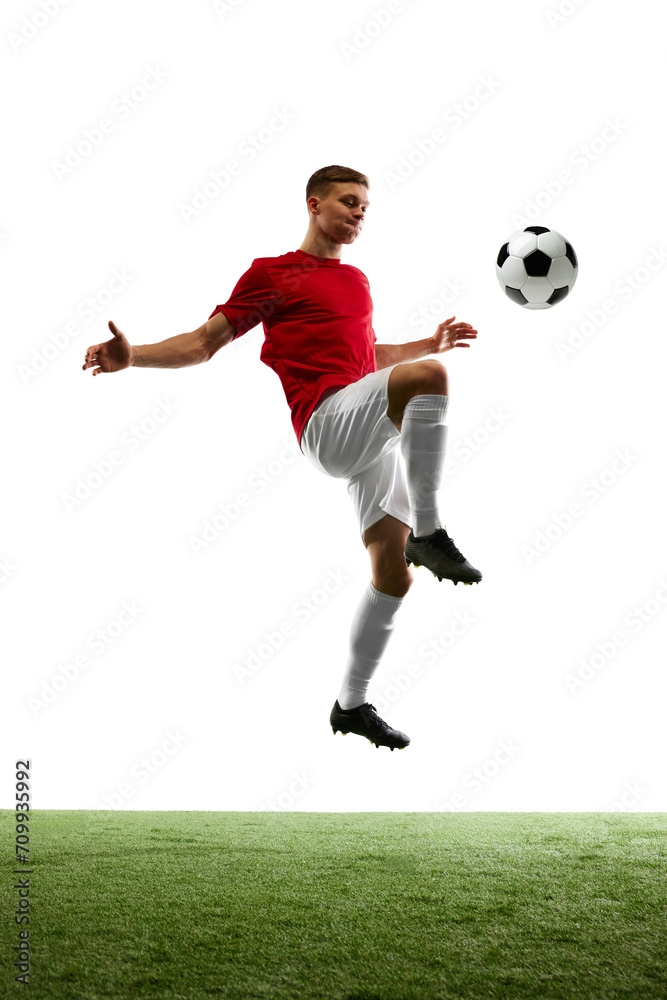Goal bound Elevation. Professional footballer kicks ball into air, aiming for opponent's gates against background of pure white and lush green grass. Concept of sport games, energy, match, movement.