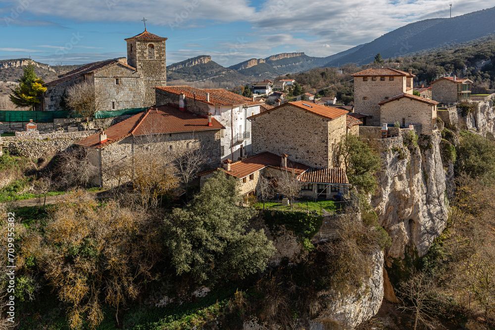 Pretty village of Puentedey with its architecture, Church of San Pelayo, roofs and vertical rock walls in the landscape, Burgos, Castilla y León, Spain.