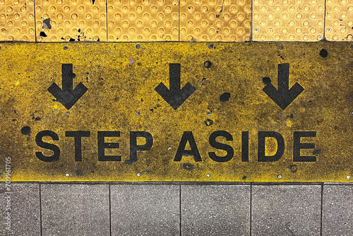 Step aside subway sign with arrows on the platform ground in the subway
