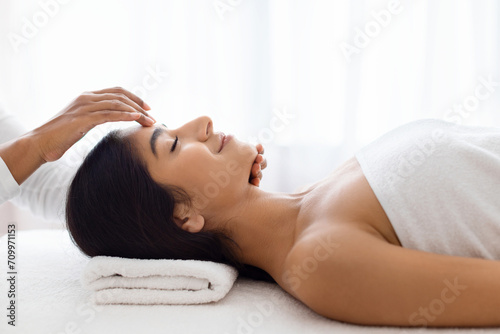 Young lady in serene relaxation during spa head treatment