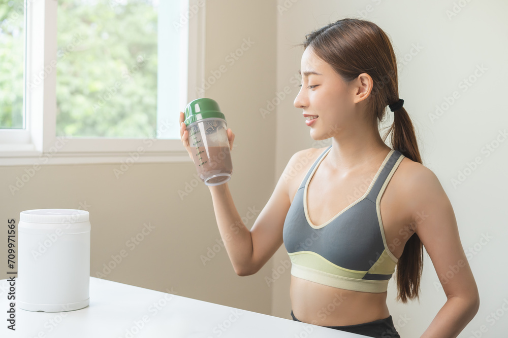 Diet meal replacement for weight loss, smile asian young woman, girl in sportswear, hand in holding protein shake bottle for drink supplement for muscle after workout at home. Healthy body care person Diet meal replacement for weight loss, smile asian young woman, girl in sportswear, hand in holding protein shake bottle for drink supplement for muscle after workout at home. Healthy body care person