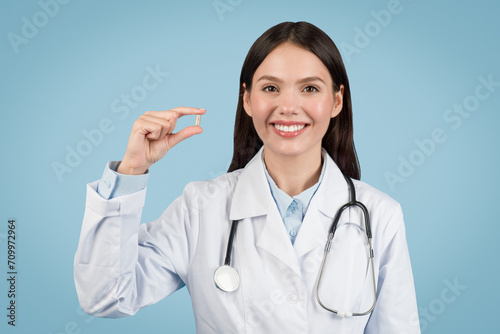 Cheerful woman doctor showing small pill  healthcare and treatment