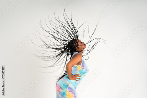 Plus size female model posing in colorful dress on white background, young African woman with curvy figure and pigtailed hairstyle, afro braids photo