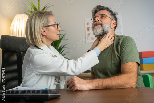 Doctor examining neck of patient in clinic office. Healthcare, consultation and doctor checking throat of patient with advice, help and solution. Medicine, health care and Indian man with neck pain