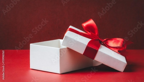 blank white present box open or gift box with red ribbons and bow over dark red background with shadow and blank space minimal conceptual 3d rendering