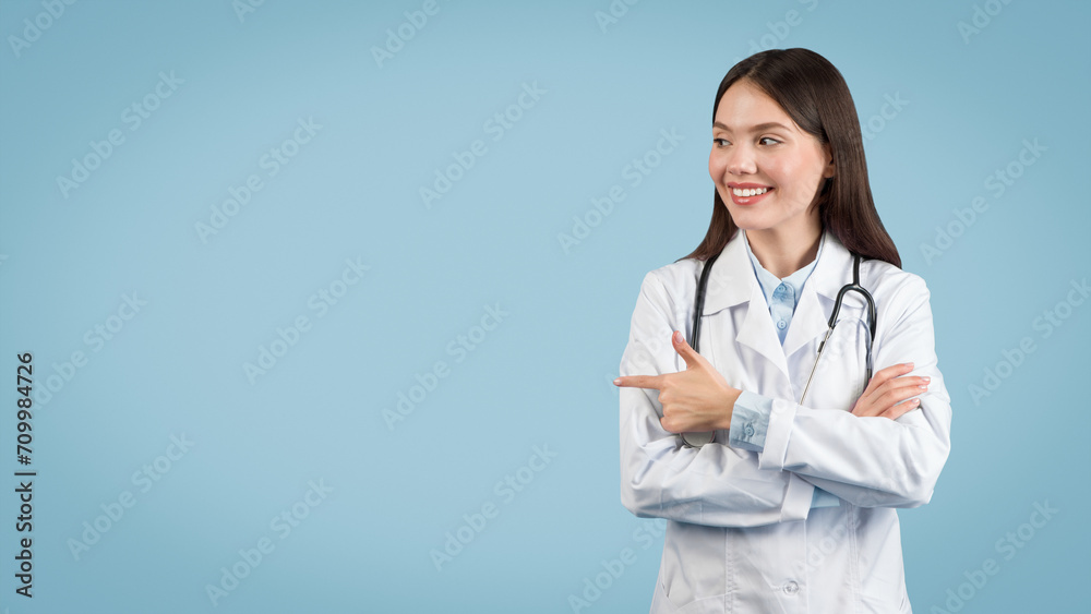 Confident female doctor pointing to the side at free space, blue background Confident female doctor pointing to the side at free space, blue background