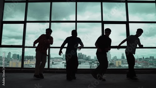 Silhouette shot of skilled choreographer group dancing together with sky scrapper or cityscape background. Young hipster team break dancing performance near window. Outdoor sport 2024. hiphop.