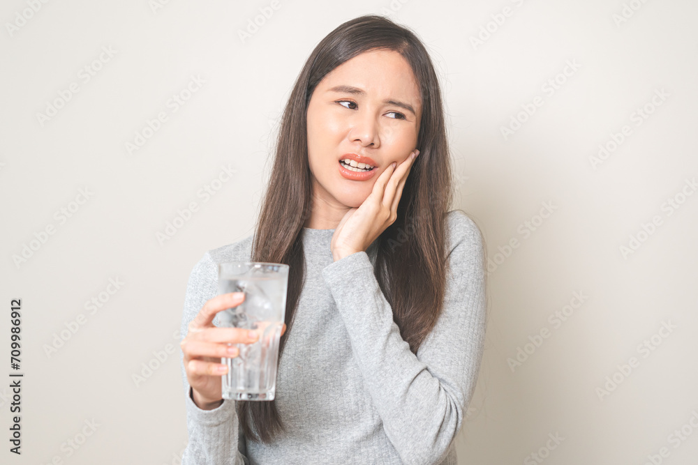 Suffering from toothache, hurt asian young woman touch cheek, face expression ache or feel pain, sensitive molar teeth, hand holding glass of water with ice, inflammation when drink cold, healthcare. Suffering from toothache, hurt asian young woman touch cheek, face expression ache or feel pain, sensitive molar teeth, hand holding glass of water with ice, inflammation when drink cold, healthcare.