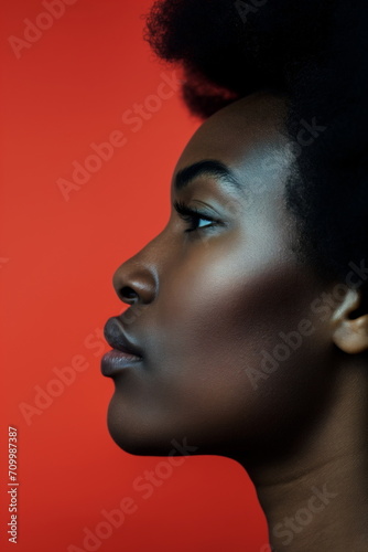 Beautiful black woman in profile view. Cropped vertical photo of young African American female on red studio background. Beauty, Black History Month concept. For banner, card, postcard, poster.