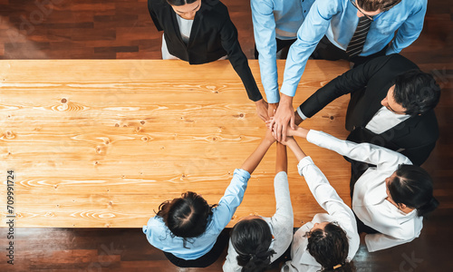 Multiracial business people make synergy hand stack together in meeting room as cooperation or team building for corporate employee in workplace. Panorama top view. Meticulous