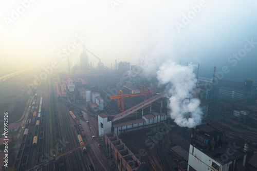 Industrial iron production factory during manifacture, aerial view from exterior,among smokes