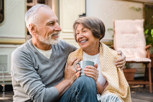 Love and care. Senior old husband covering his wife with blanket to comfort warm her up while they are traveling by trailer camper van caravanning on motor home