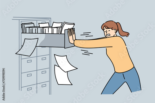 Woman closes overflowing filing cabinet, suffering from overabundance of paperwork and bureaucracy. Girl pushes safe with papers, for concept need for digitalization of data to get rid of bureaucracy