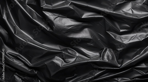 Wrinkled black plastic texture, black background wallpaper. Crumpled plastic surface